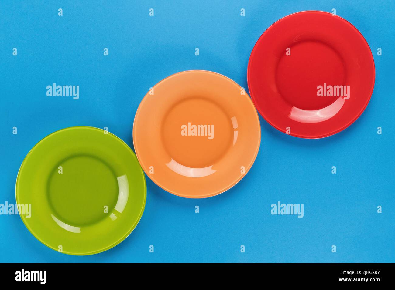 Empty bright colored plates row on blue background top view with copy space Stock Photo