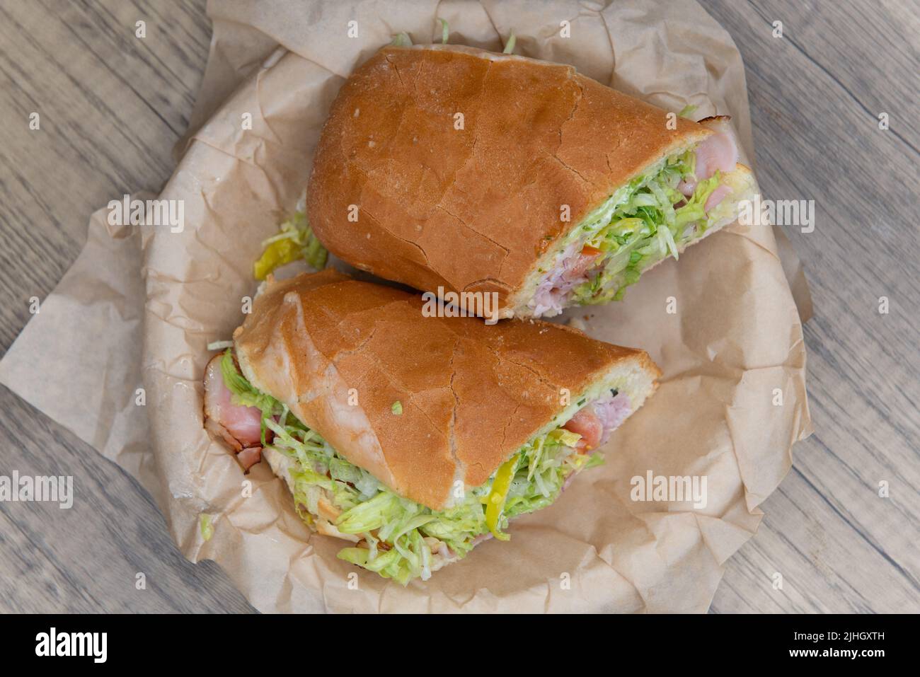 Overhead view of loaded ham sandwich with provolone cheese, tomato, mayo, and red onion inside an Italian Roll for a hearty lunch meal. Stock Photo