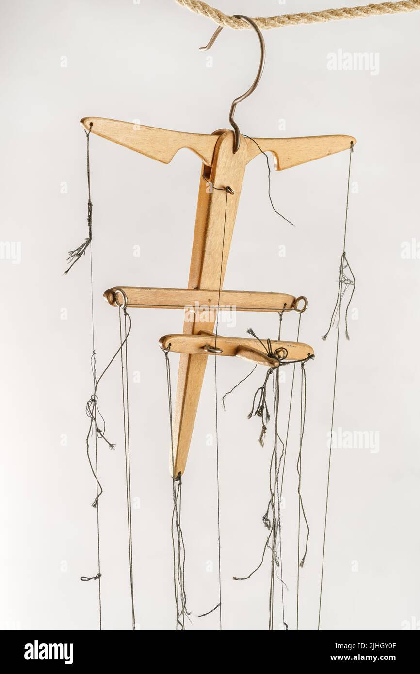 Wooden puppet control with black threads down from it on white background Stock Photo