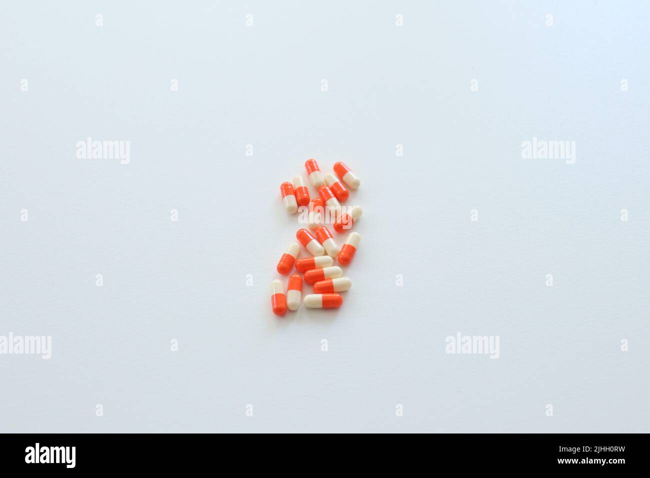Scattered capsule pills isolated on white background. Orange and white colored drugs. Treatment method idea concept. suicidal metaphor meaning. Stock Photo