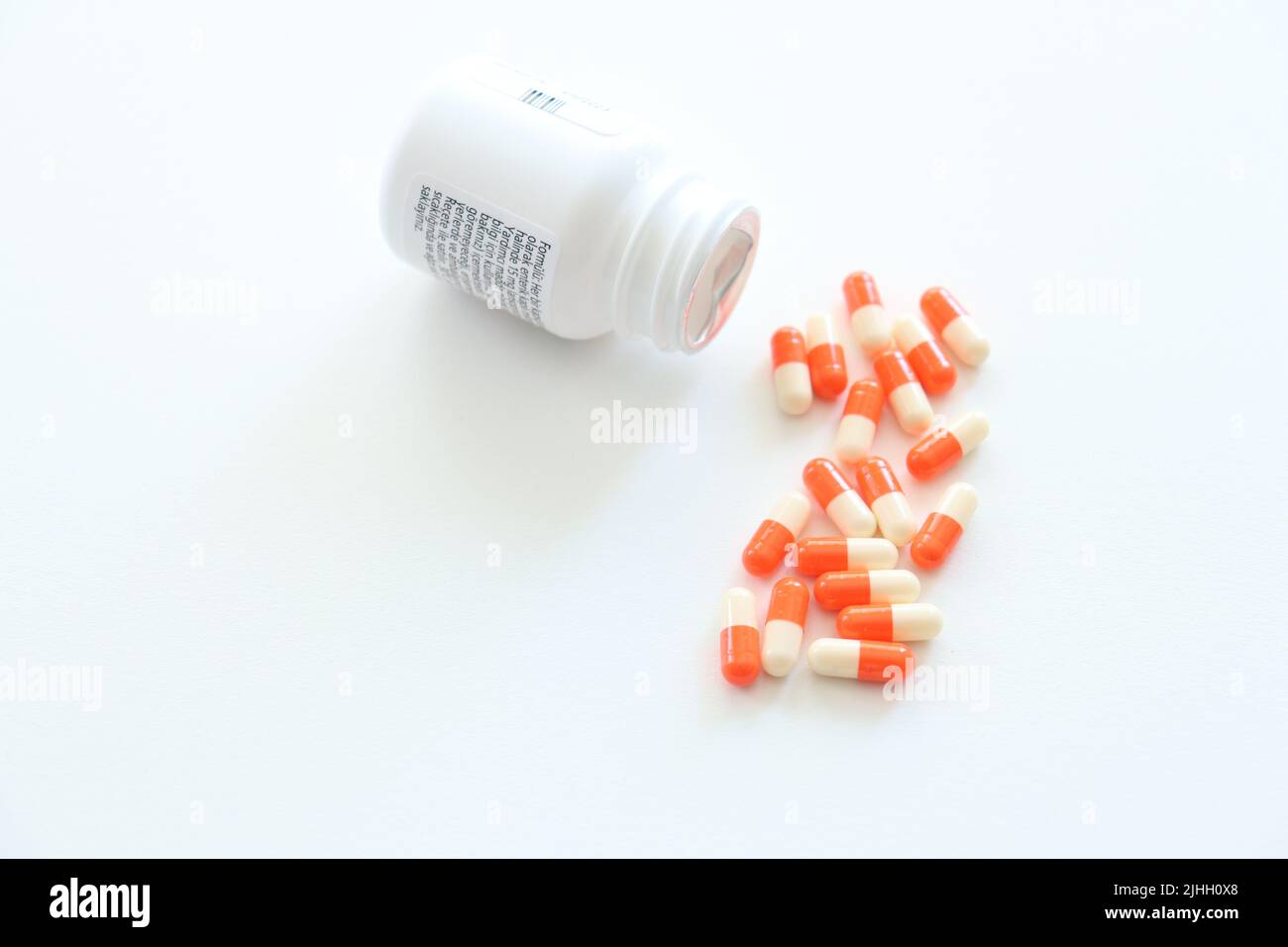 Capsules spilled from the medicine box on an isolated white background. Orange and white pills. Suicidal idea concept. Vitamins, supplements. Nobody. Stock Photo