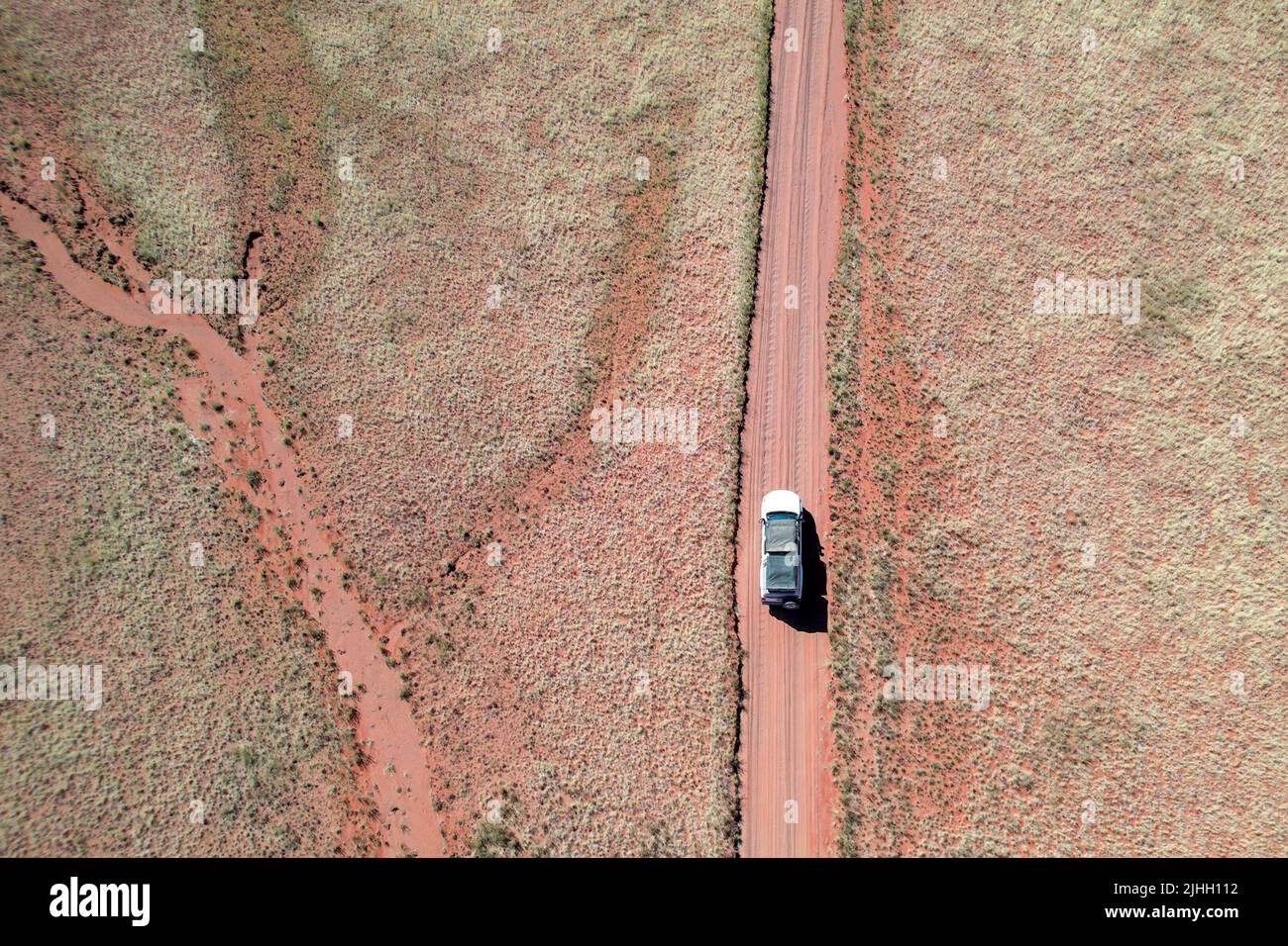 Drone shot of a car on a red gravel road in Namibia Africa Stock Photo