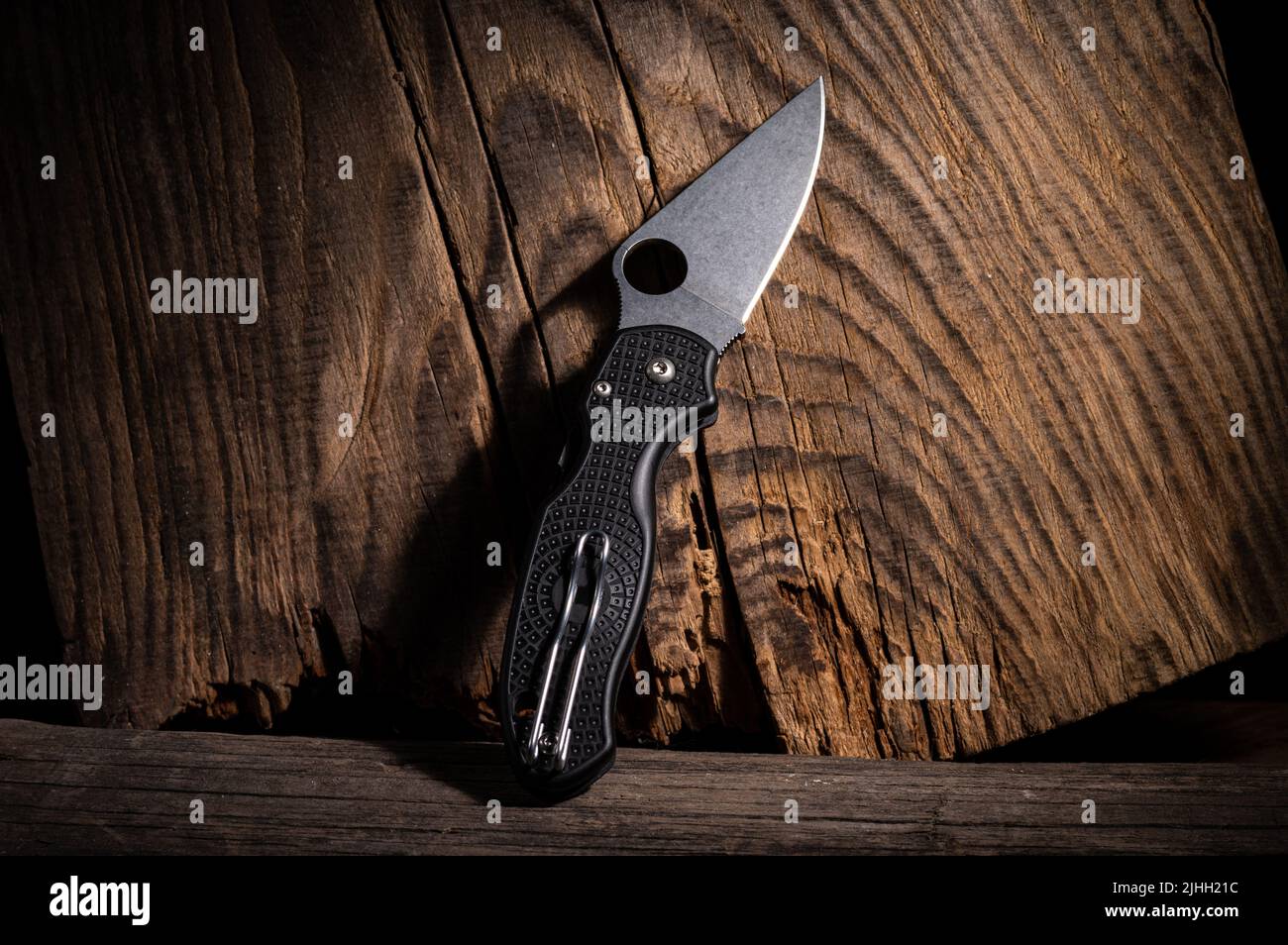 Folding pocket knife with carrying clip. Knife on a wood background