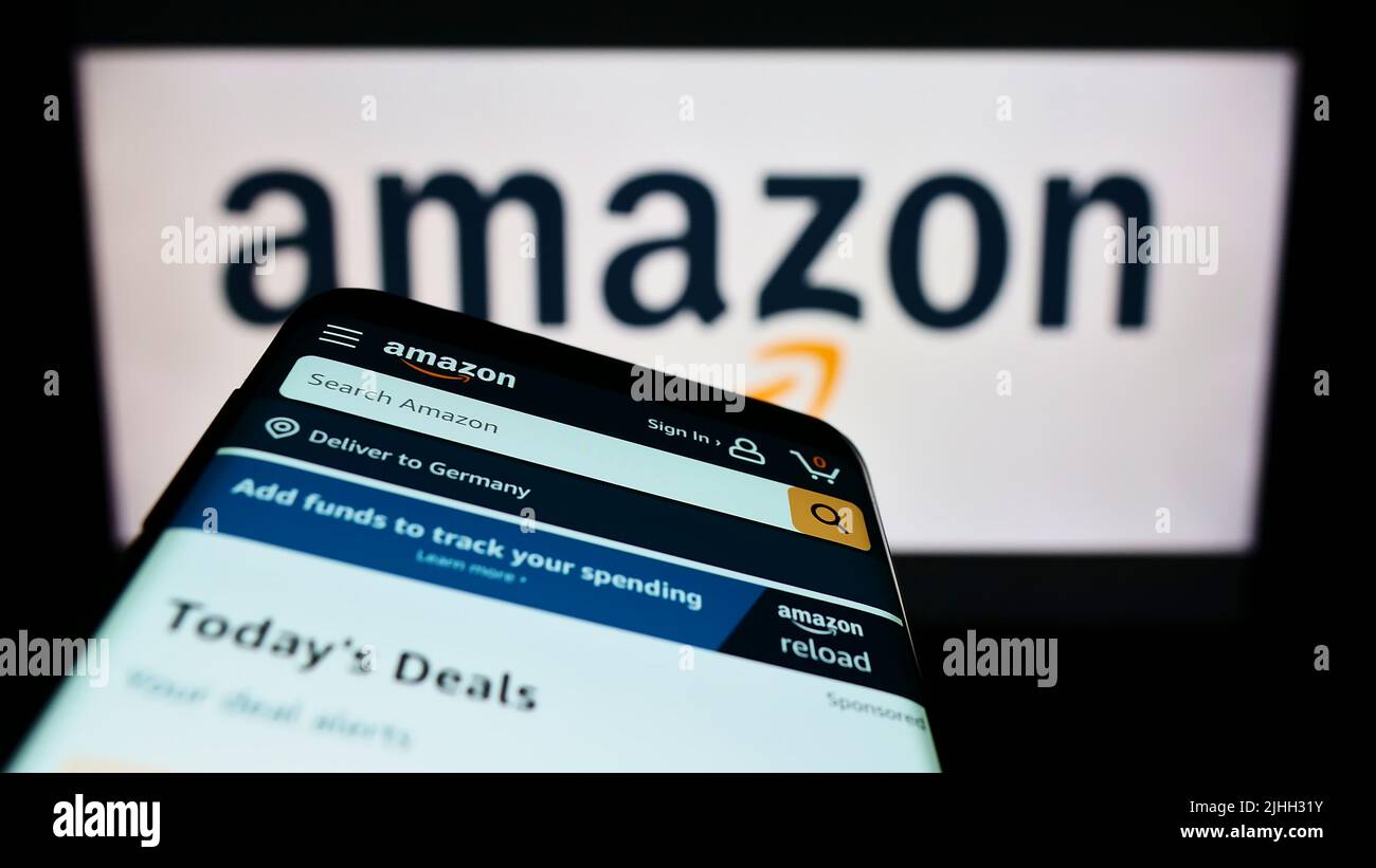 Mobile phone with website of American technology company Amazon.com Inc. on screen in front of logo. Focus on top-left of phone display. Stock Photo