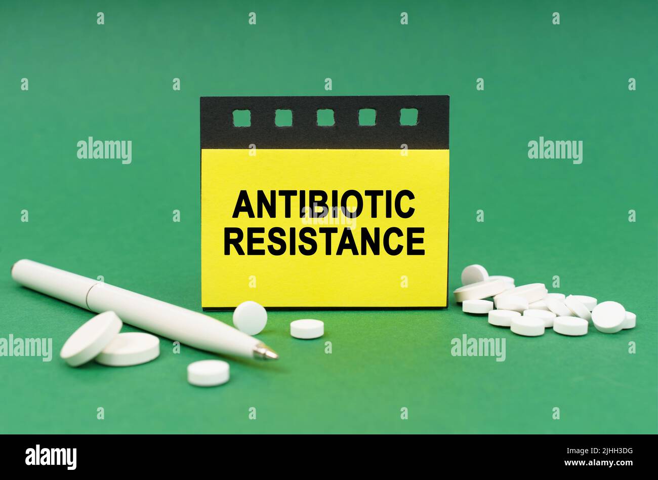 Medical concept. On the green surface are tablets, a pen and stickers with the inscription - ANTIBIOTIC RESISTANCE Stock Photo