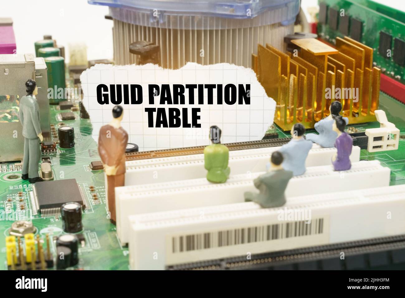 Technology and computer concept. On the motherboard there are figures of people and torn paper with the inscription - GUID Partition Table Stock Photo