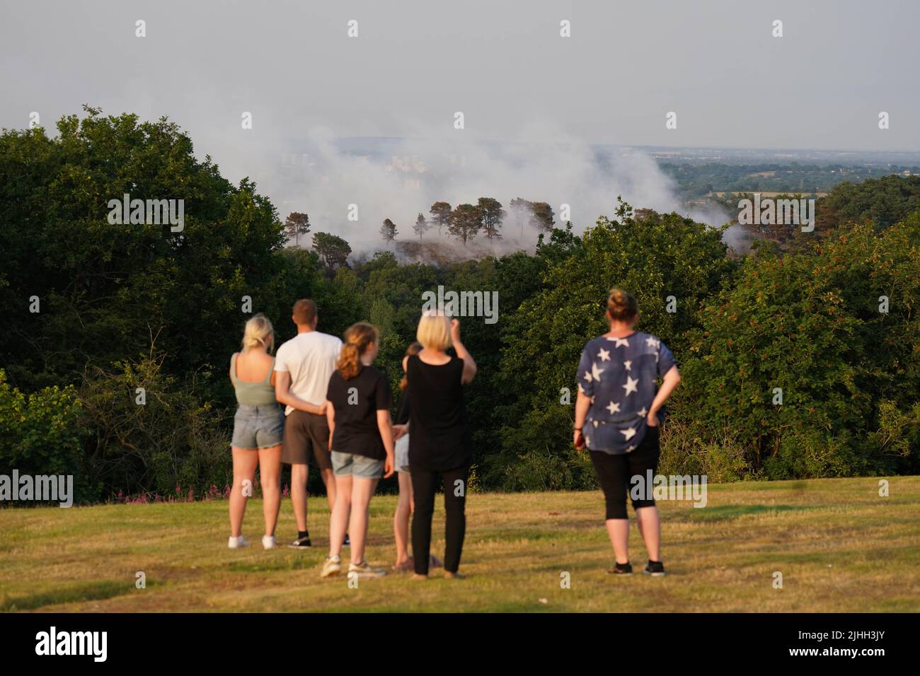 People watch a large wildfire that has broken out in woodland at Lickey Hills Country Park on the edge of Birmingham. About sixty firefighters are tackling the blaze which broke out at the beauty spot earlier today. Picture date: Monday July 18, 2022. Stock Photo