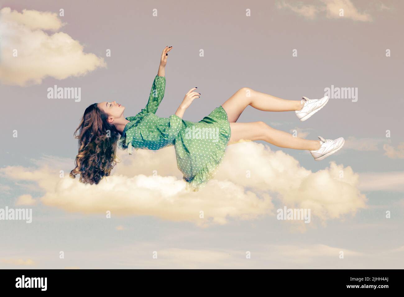 Floating in air. Relaxed girl in vintage ruffle dress levitating keeping eyes closed, sleeping while flying mid-air having comfortable peaceful dream in sky. collage composition on day cloudy blue sky Stock Photo