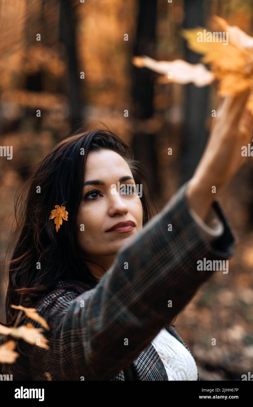 Portrait brunette woman with fall yellow leaves in long hair on autumn ...
