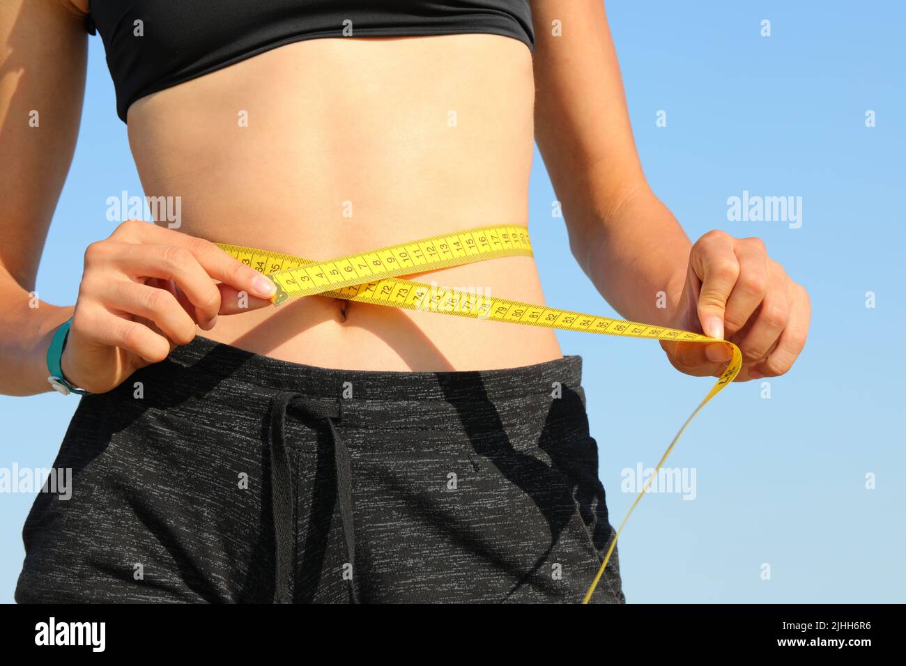 belly of the thin girl while measuring her waist with the yellow tape measure Stock Photo