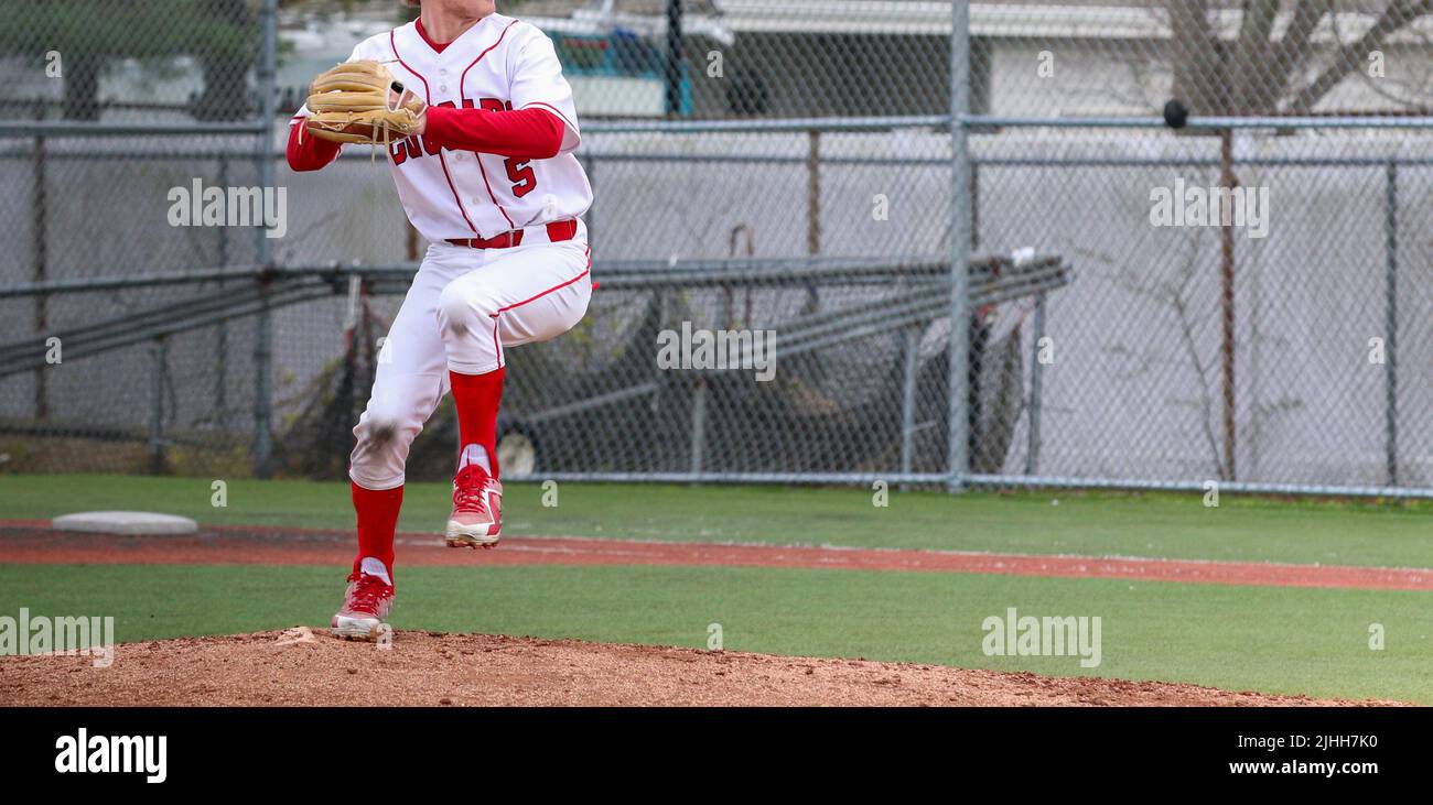 A high school baseball pitcher is pitching from the pitchers mound