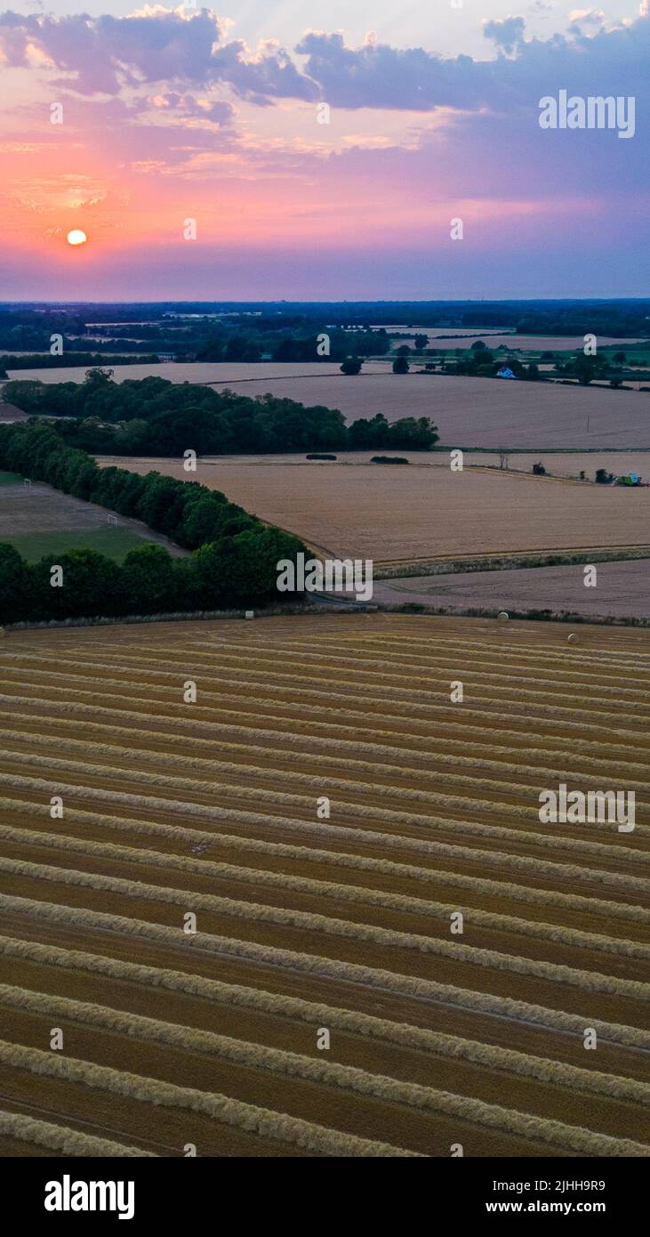 Aerial portrait Sunset in Suffolk with freshly harvested wheat field in the foreground Stock Photo