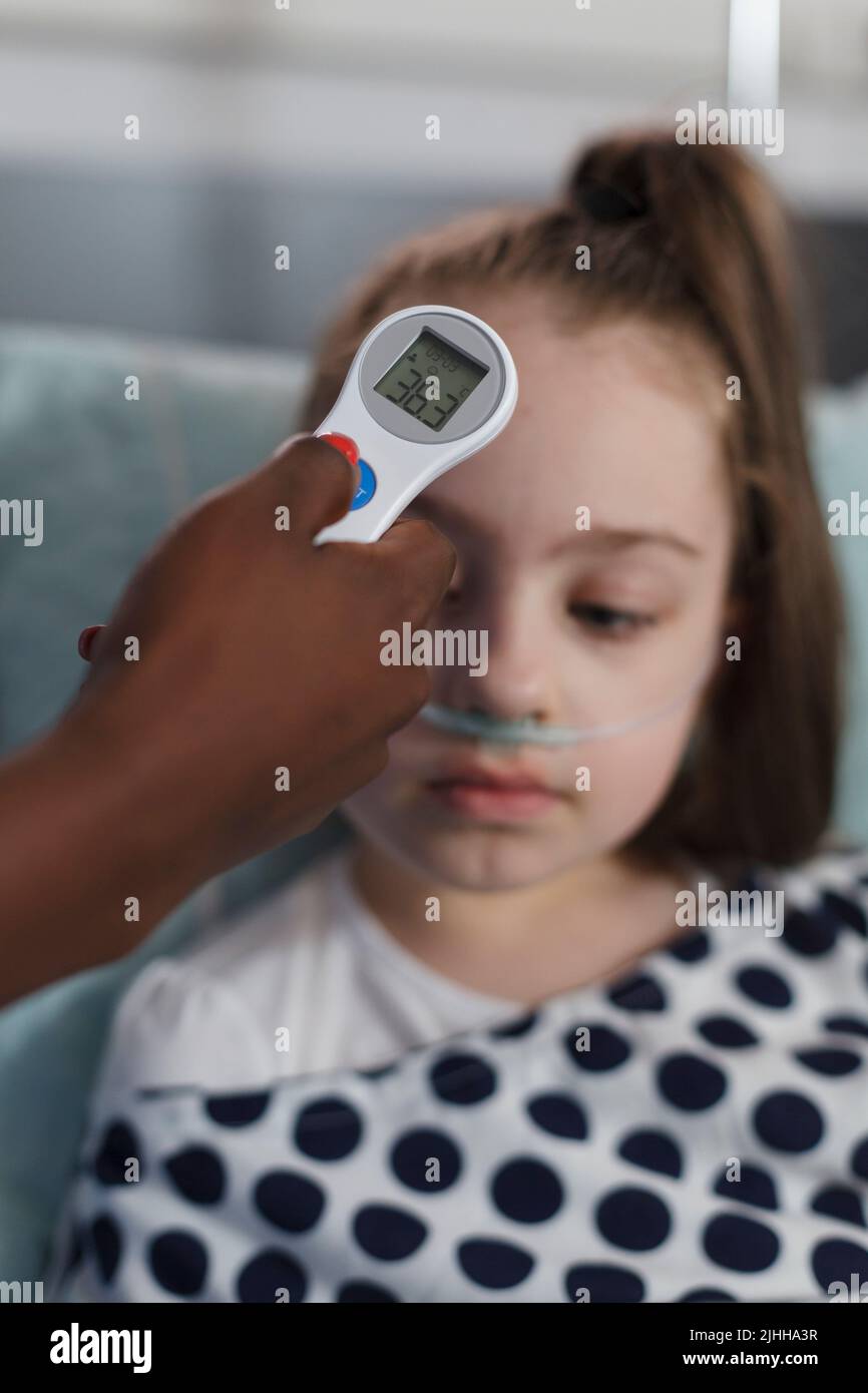 Close up shot of pediatric hospital nurse measuring sick little girl body temperature using