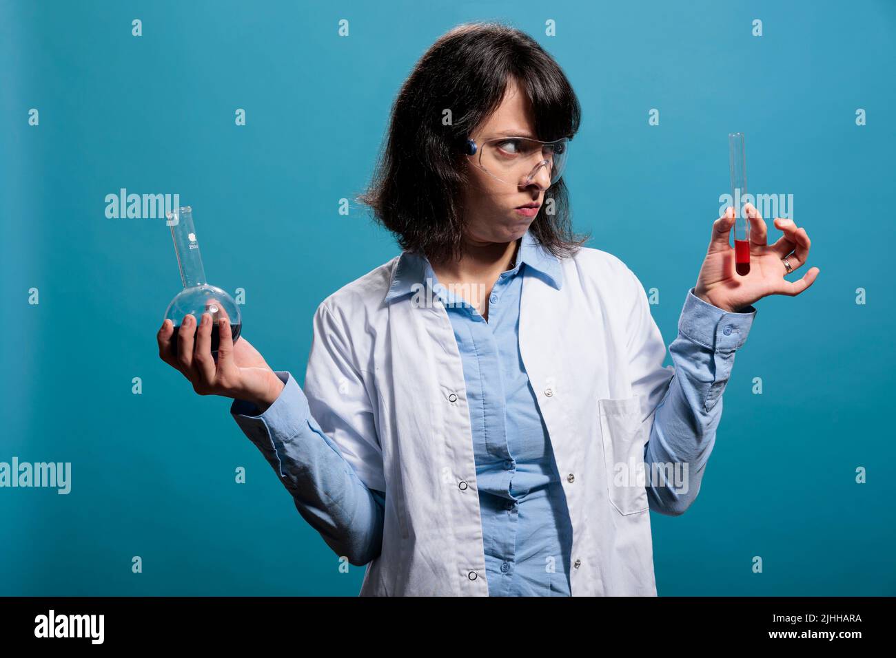 Upset angry professional laboratory chemist holding chemistry glass