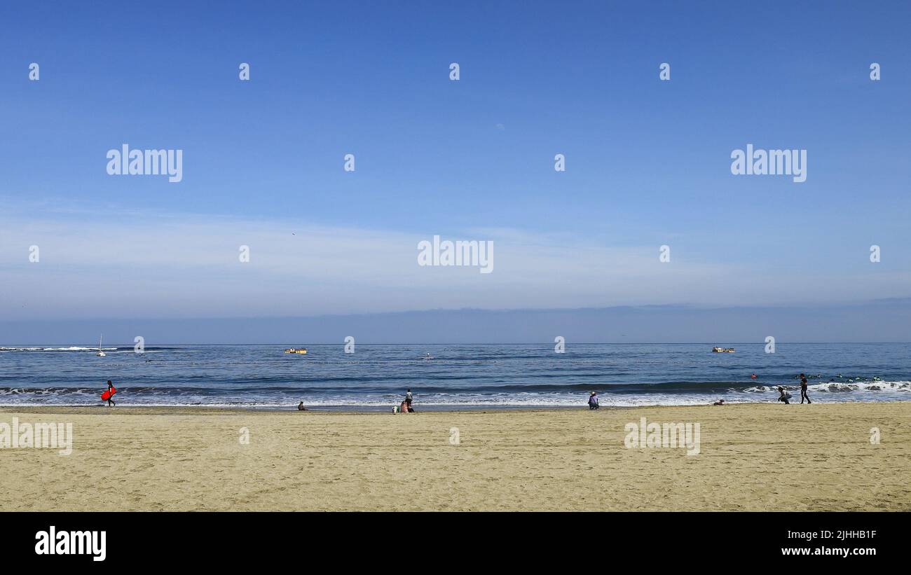 Beach scenery in autumn, a group of people having fun relaxing by the sea. Stock Photo