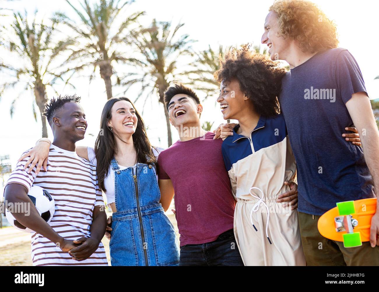 Group of five happy young people standing outside together on summer vacation Stock Photo