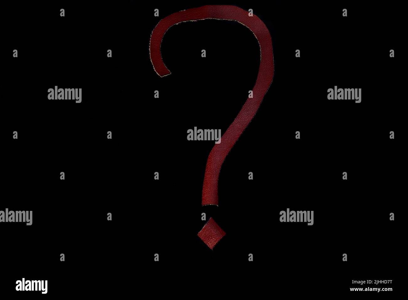 Hand cut red leather question mark on a saturated black background. Stock Photo