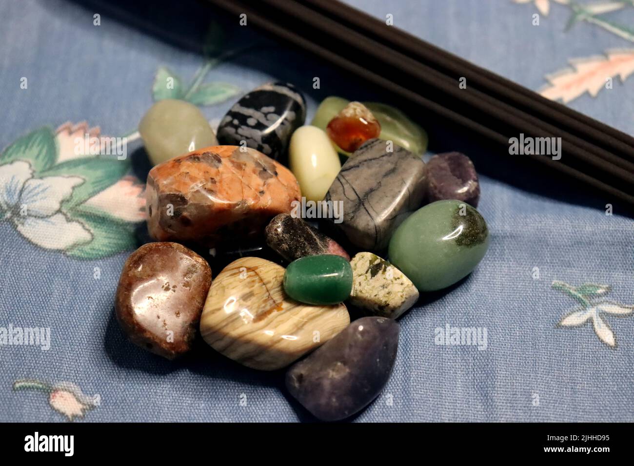 Witchcraft isn't always black and spooky. Here's a setup with polished stoned and incense on a blue floral background. Stock Photo