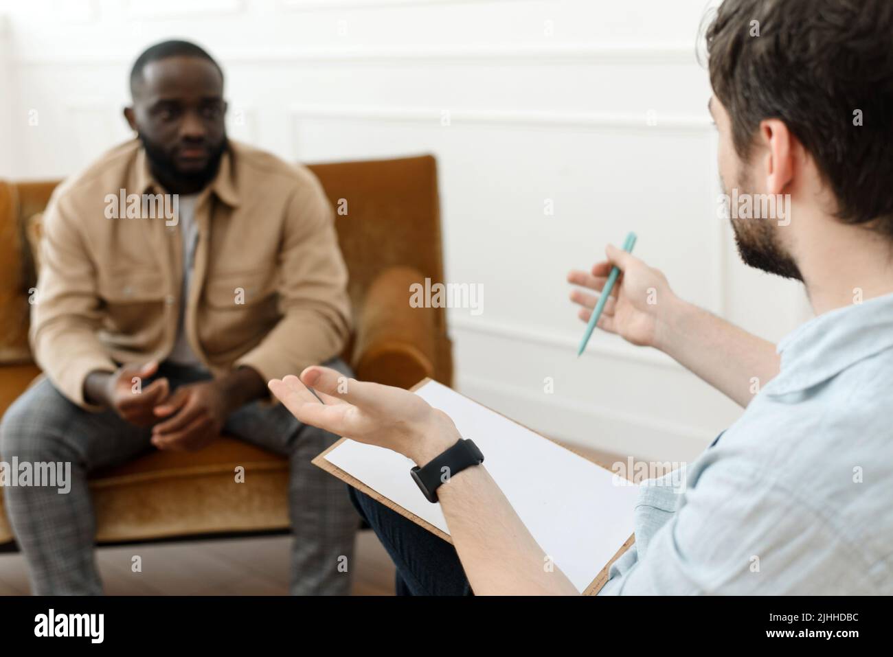 The therapist takes notes while talking to a depressed male patient and ...