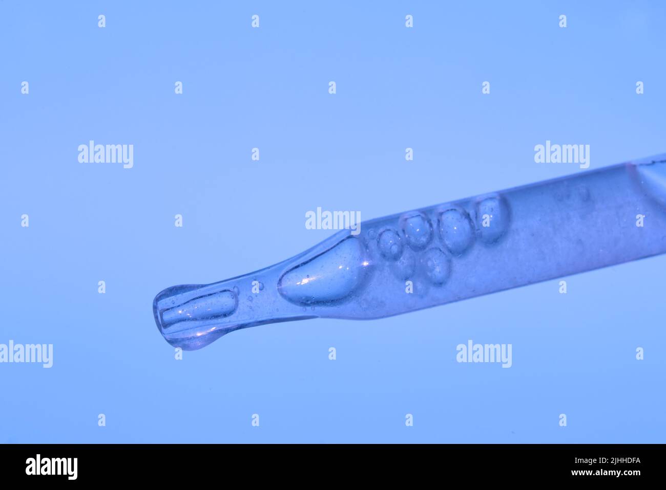 Pipette with a thick extract on a blue background. This is the consistency of the serum. The concept of a plant extract for cosmetic and therapeutic purposes. High quality photo Stock Photo