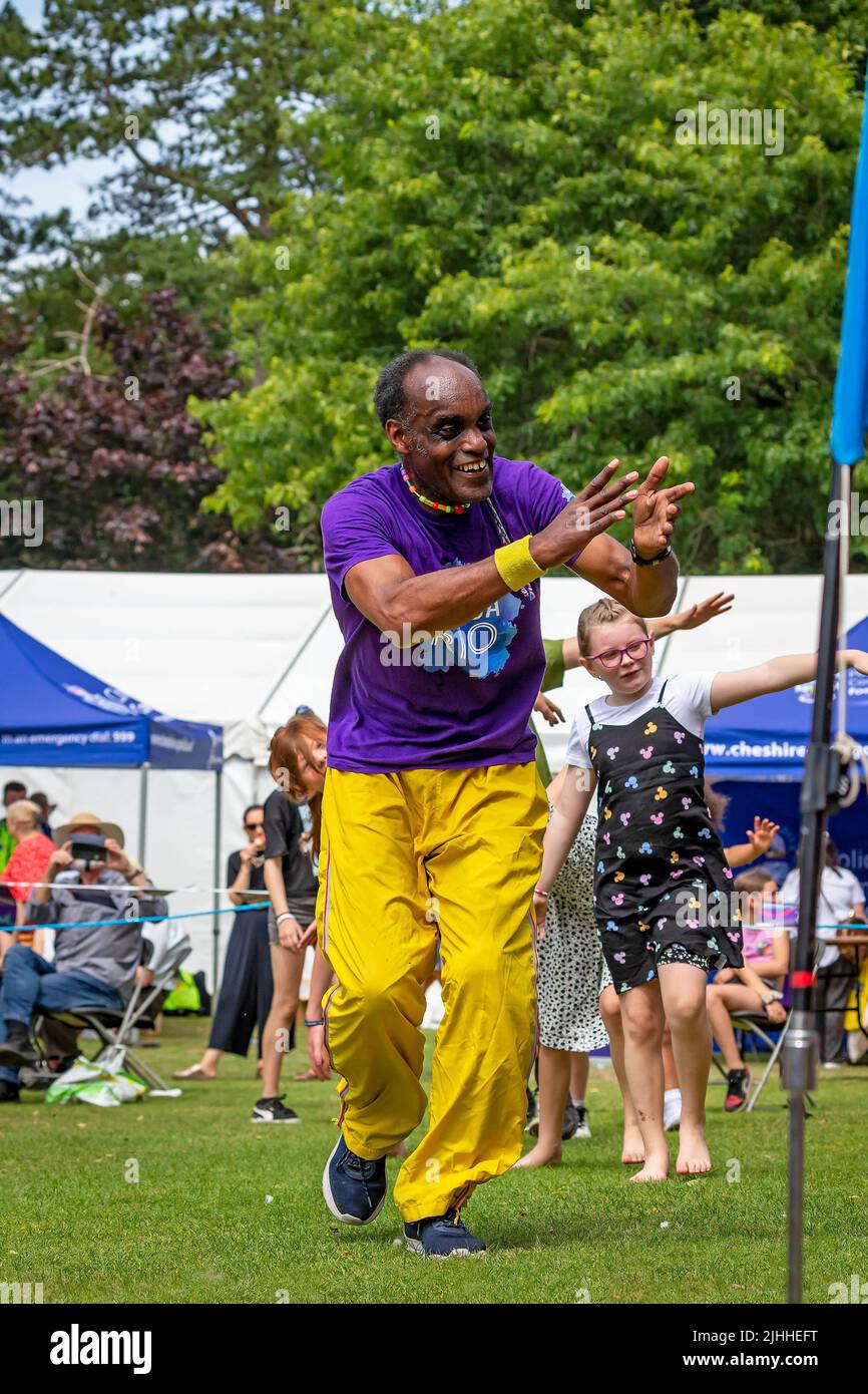 Colourful black man leads the children in dance with Batida Rio Samba Band at Disability Awareness Day Stock Photo