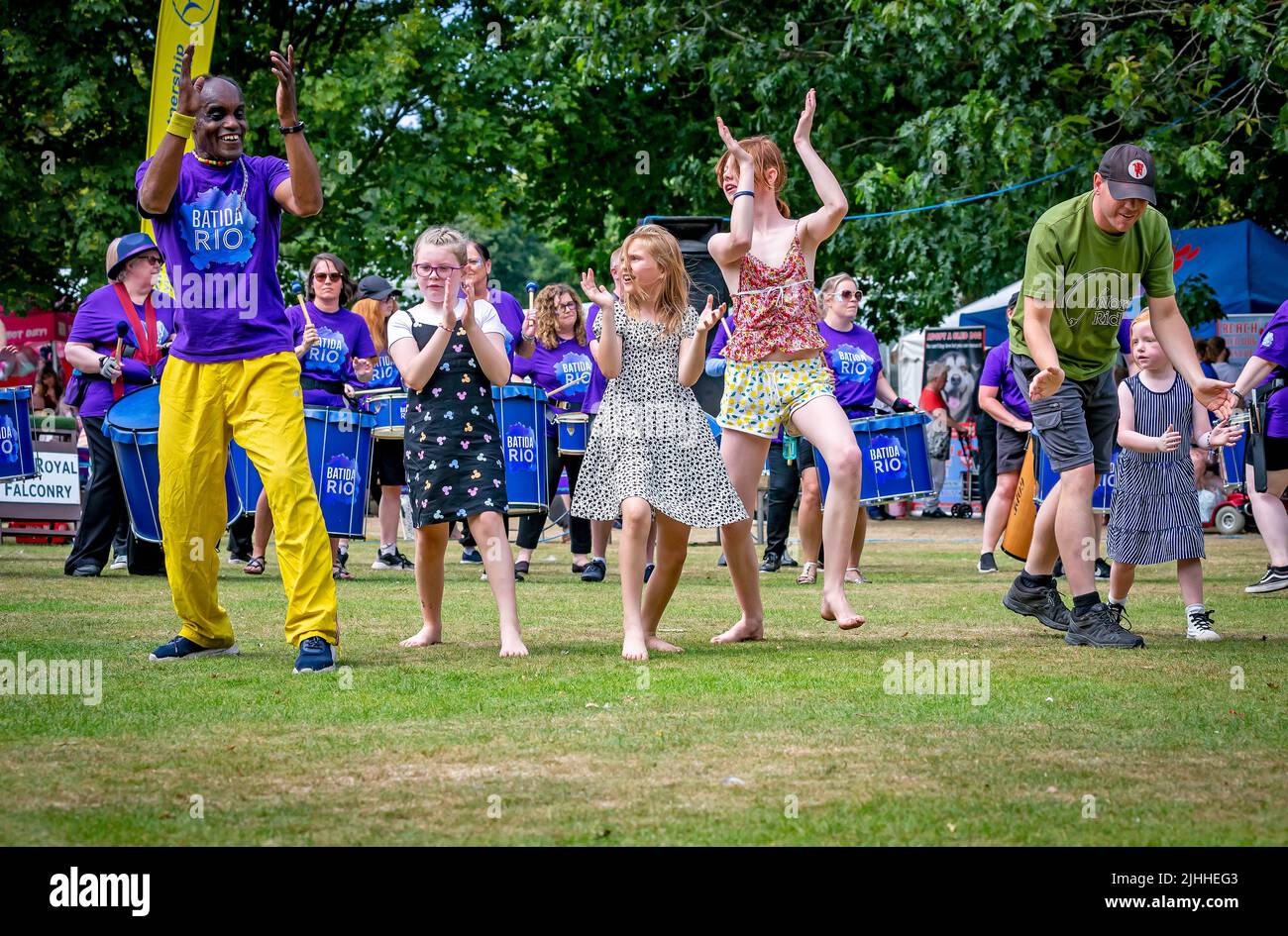 Colourful black man leads the children in dance with Batida Rio Samba Band at Disability Awareness Day 2022 Stock Photo