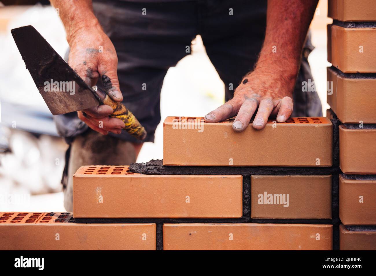 Builder laying bricks on construction site Stock Photo