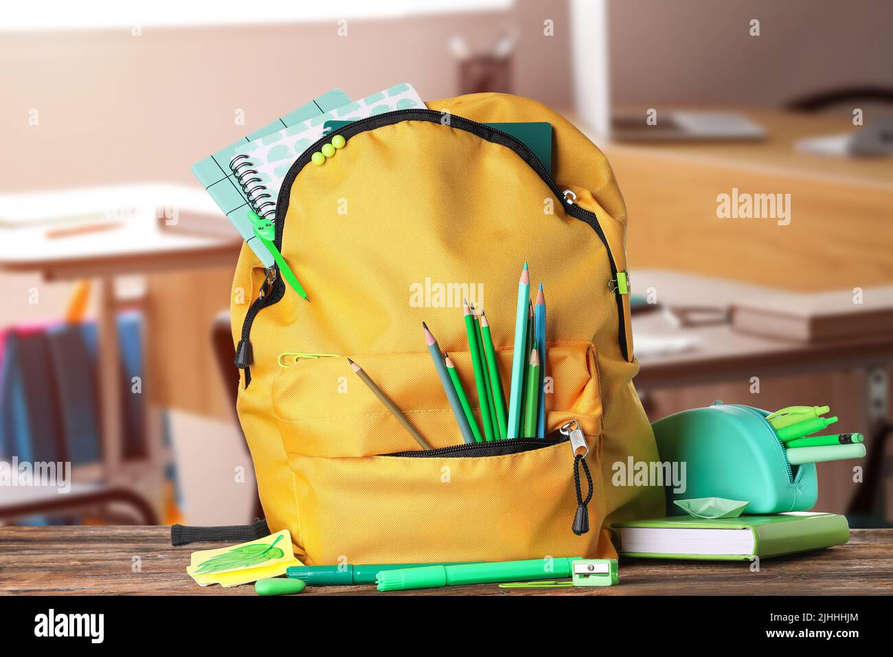 School backpack and stationery on table in classroom Stock Photo