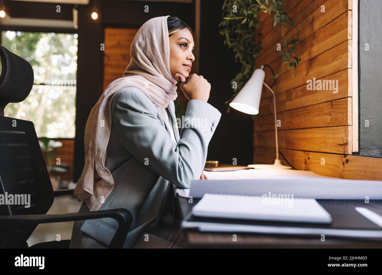 Ambitious Muslim designer thinking of creative ideas while working with architectural blueprints in a modern office. Innovative businesswoman wearing Stock Photo