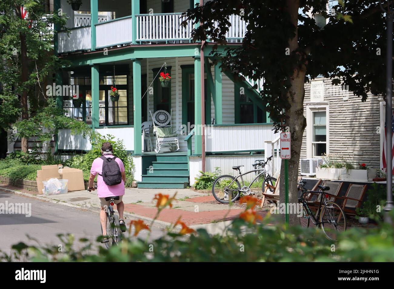 A bicyclist passing one of hundreds of beautiful houses at Chautauqua Institution, Chautauqua,  NY, June 2022 Stock Photo