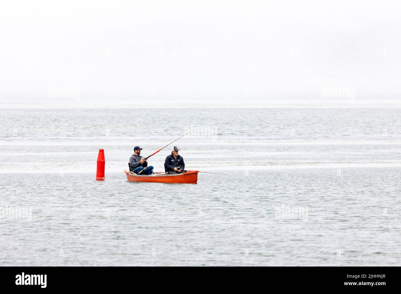 Two Fishermen in small red boat Stock Photo