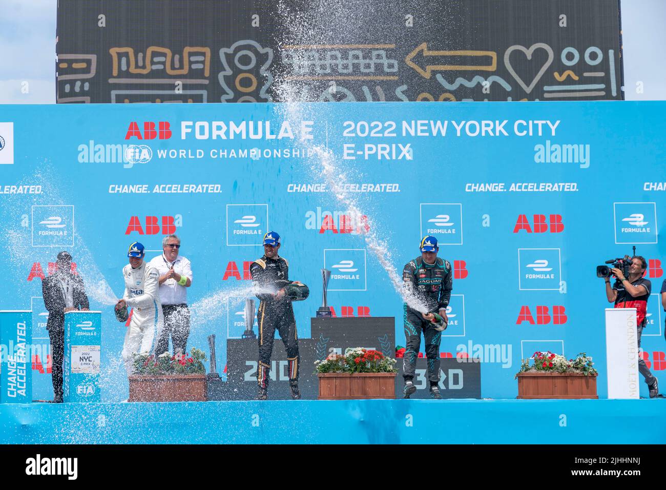 NEW YORK, NY - JULY 17: First place winner Antonio Felix Da Costa (C) (car no. 13) of DS Techeetah, who secured his first win of the season, along with second place new championship leader Stoffel Vandoorne (L) (Car no. 5) of Mercedes EQ and third place Mitch Evans (R) (car no. 9) of Jaguar TCS Racing celebrate on the podium with champagne during the ABB FIA Formula E Championship, New York City E-Prix Season 8 Round 12, on July 17, 2022 in the Brooklyn borough of New York City. Stock Photo