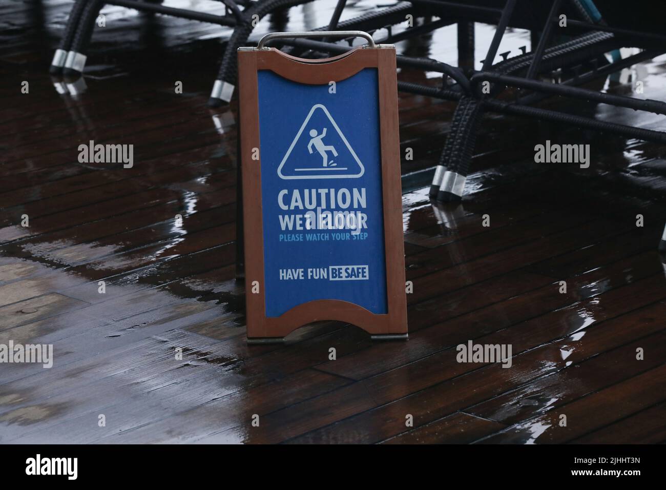 Wet floor caution sign on walkway near the building after raining. Warning yellow plastic caution wet floor sign on the ground with copy space. Stock Photo