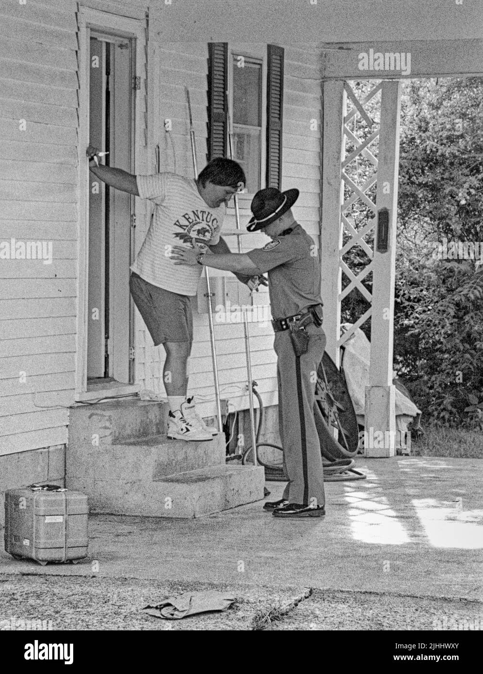 Russell Springs Police Department Patrolman Daniel Garland (right) helps Troy Scott Stephens, 32, of 2710 E. Hwy. 619 in Russell Springs, down the steps of a house on Main Street while taking him into custody following an alleged domestic violence incident on Monday, June 3, 1996 in Russell Springs, Russell County, KY, USA. Stephens walked with a limp due at least partially to an injury sustained to his left leg, but it was unclear if he suffered the leg injury during the alleged domestic violence altercation or prior to that incident. (Apex MediaWire Photo by Billy Suratt) Stock Photo