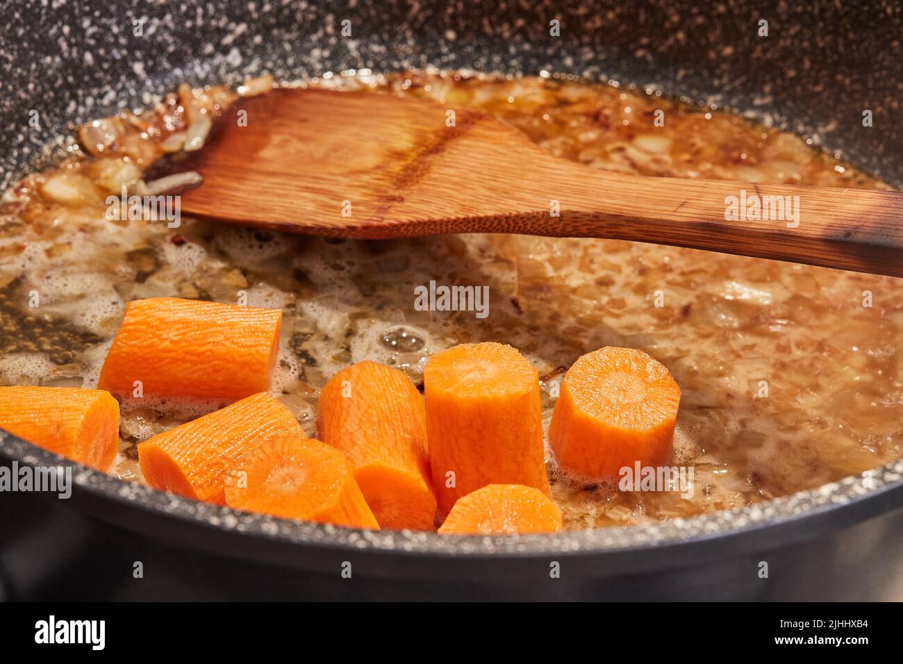 Carrots are fried in pan on gas stove to make stewed fish with