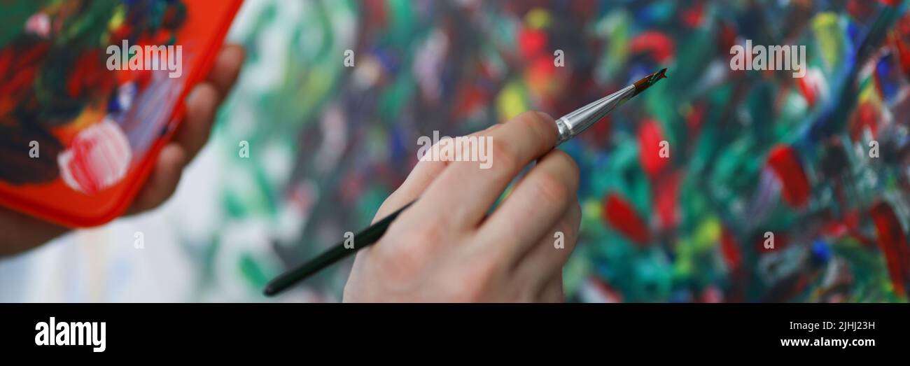 Artist apply oil paint on canvas, painter use brush with red paint