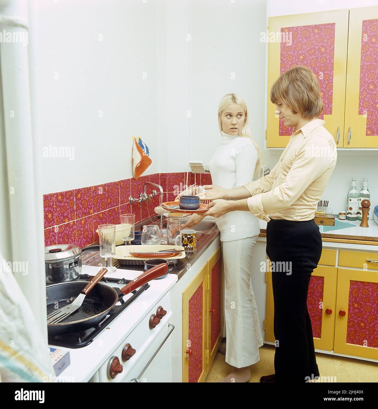 ABBA. Agnetha Fältskog. Singer. Member of the pop group ABBA. Born 1950. Pictured here at home with her fiancé Björn Ulvaeus 1970 whom she married on 6 July 1971. The kitchen-sink is full of plates and glasses and it looks as if the argue over who should clean it up. Stock Photo