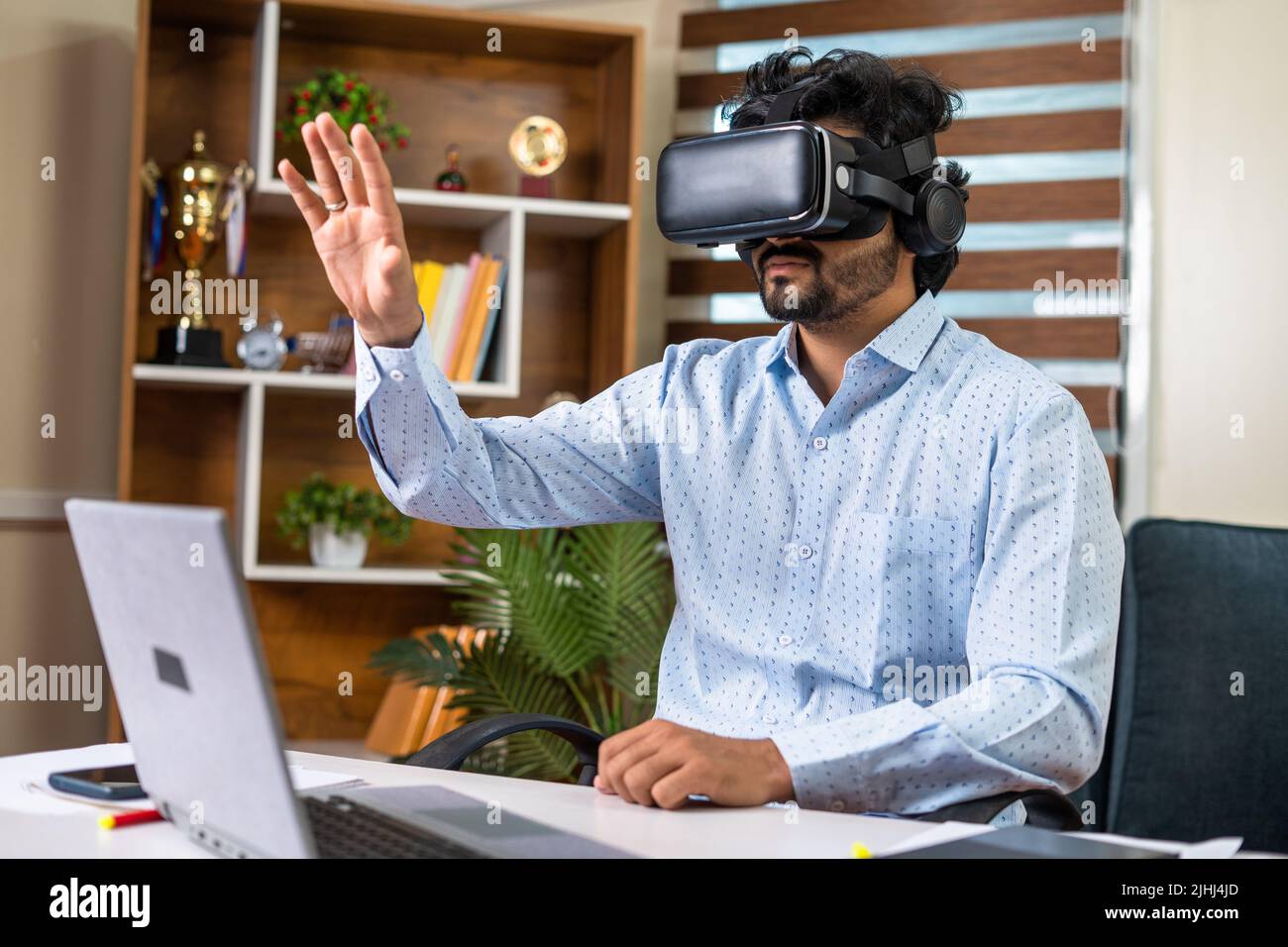 young businessman busy using VR or virtual reality headset for meeting at office with hand gestures - concept of technology, metaverse and futuristic Stock Photo