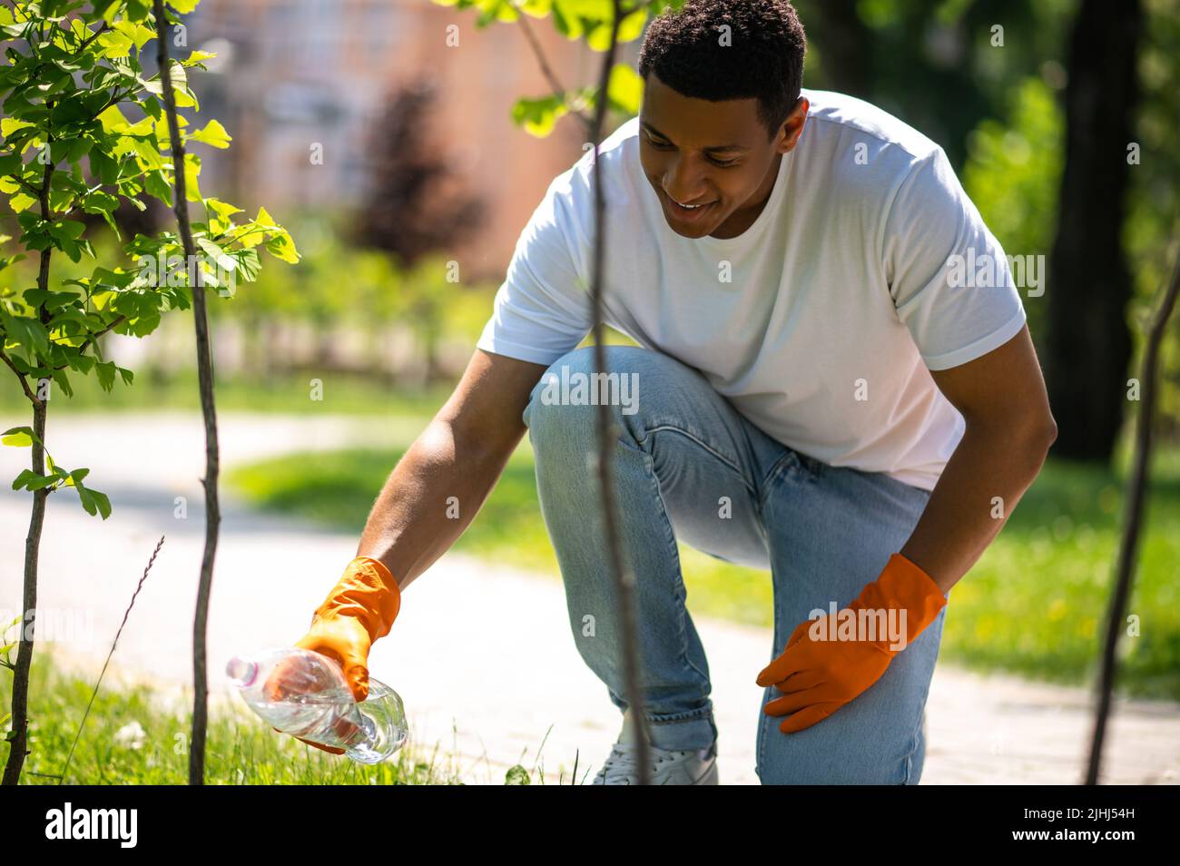Guy watering tree seedlings in park Stock Photo