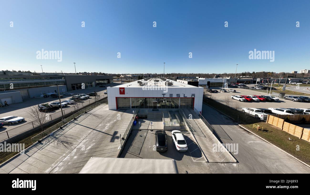 The front of a Tesla EV Dealership and Store is seen on a clear, sunny day. Stock Photo