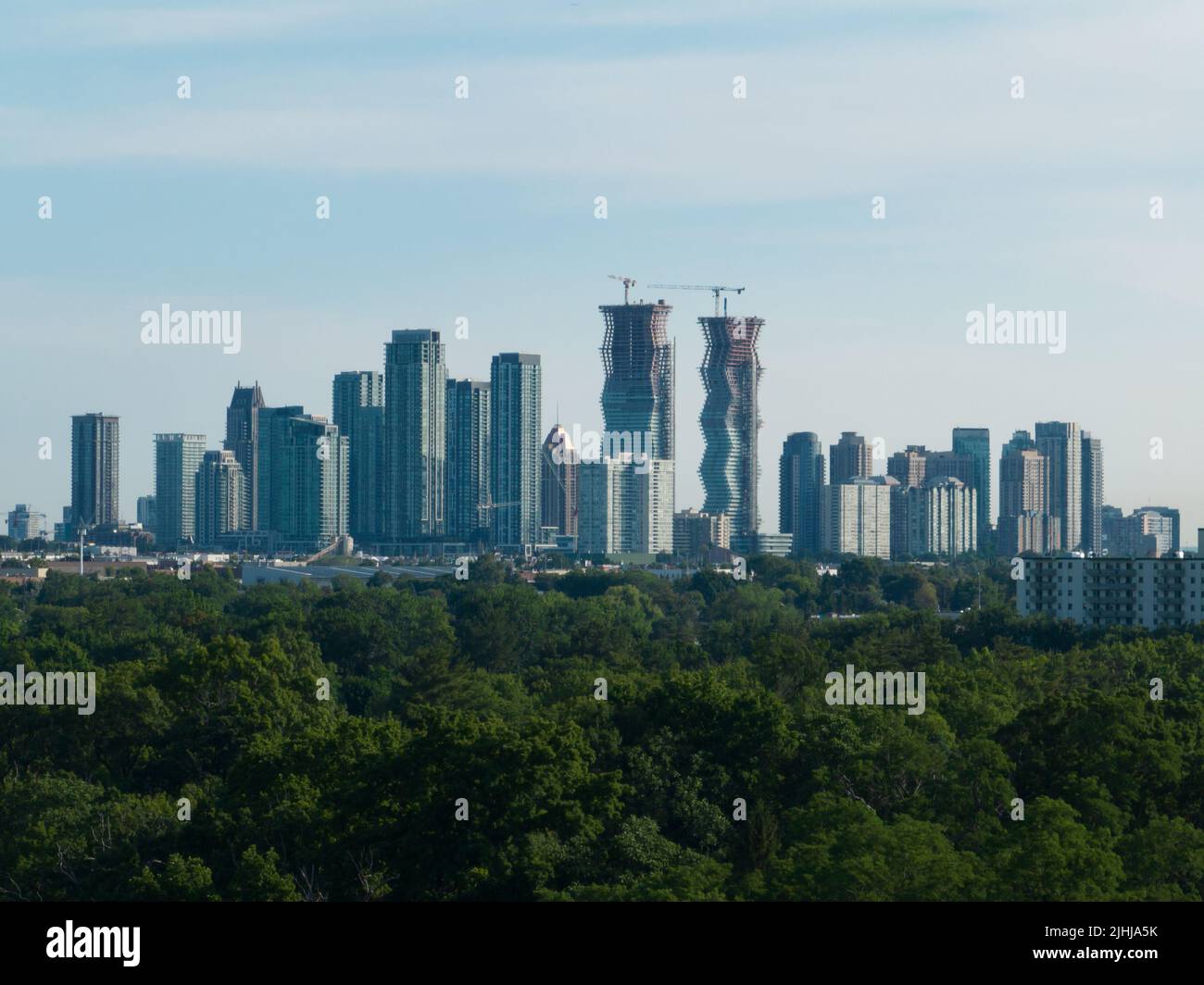 A modern cityscape skyline is seen on the horizon of a sunny day. New buildings and condos are under construction. Stock Photo