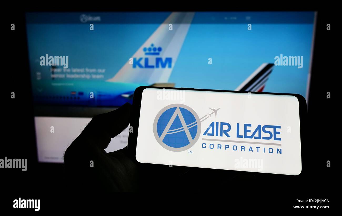 Person holding mobile phone with logo of US leasing company Air Lease Corporation (ALC) on screen in front of web page. Focus on phone display. Stock Photo