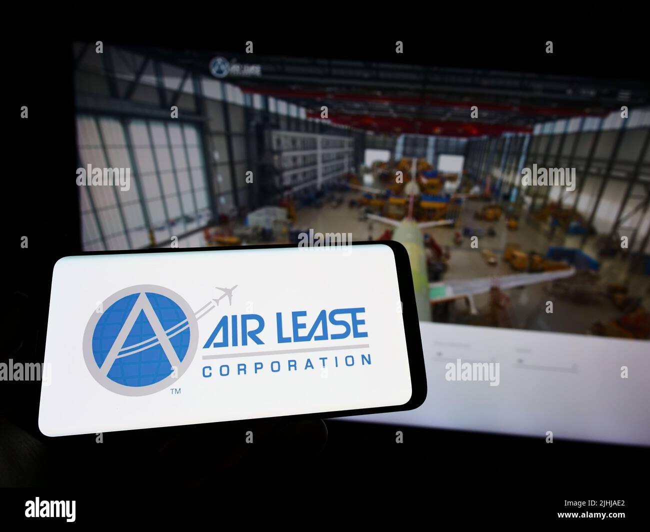 Person holding cellphone with logo of American leasing company Air Lease Corporation (ALC) on screen in front of webpage. Focus on phone display. Stock Photo