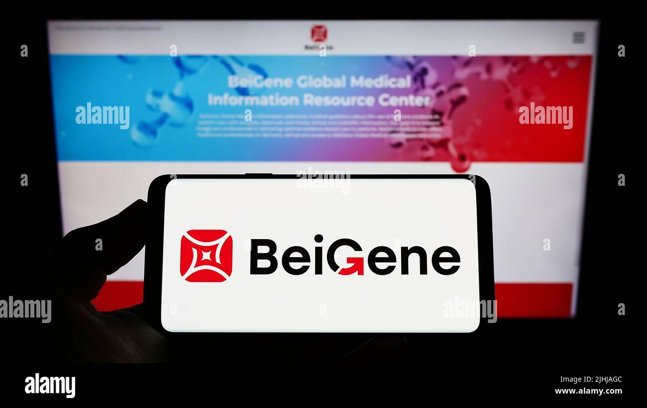 Person holding smartphone with logo of Chinese biotechnology company Beigene Ltd. on screen in front of website. Focus on phone display. Stock Photo