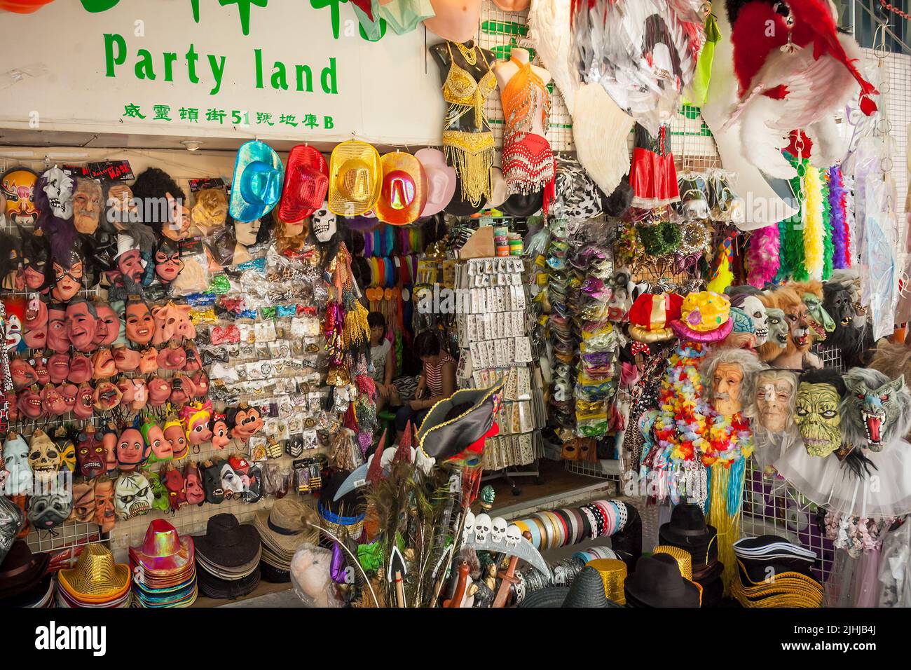 A street market stall sells party and Halloween masks, costumes and