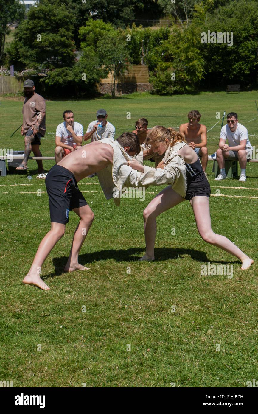 A young teenage girl wrestling with a boy competing in the Grand Cornish Wrestling Tournament on the picturesque village green of St Mawgan in Pydar i Stock Photo