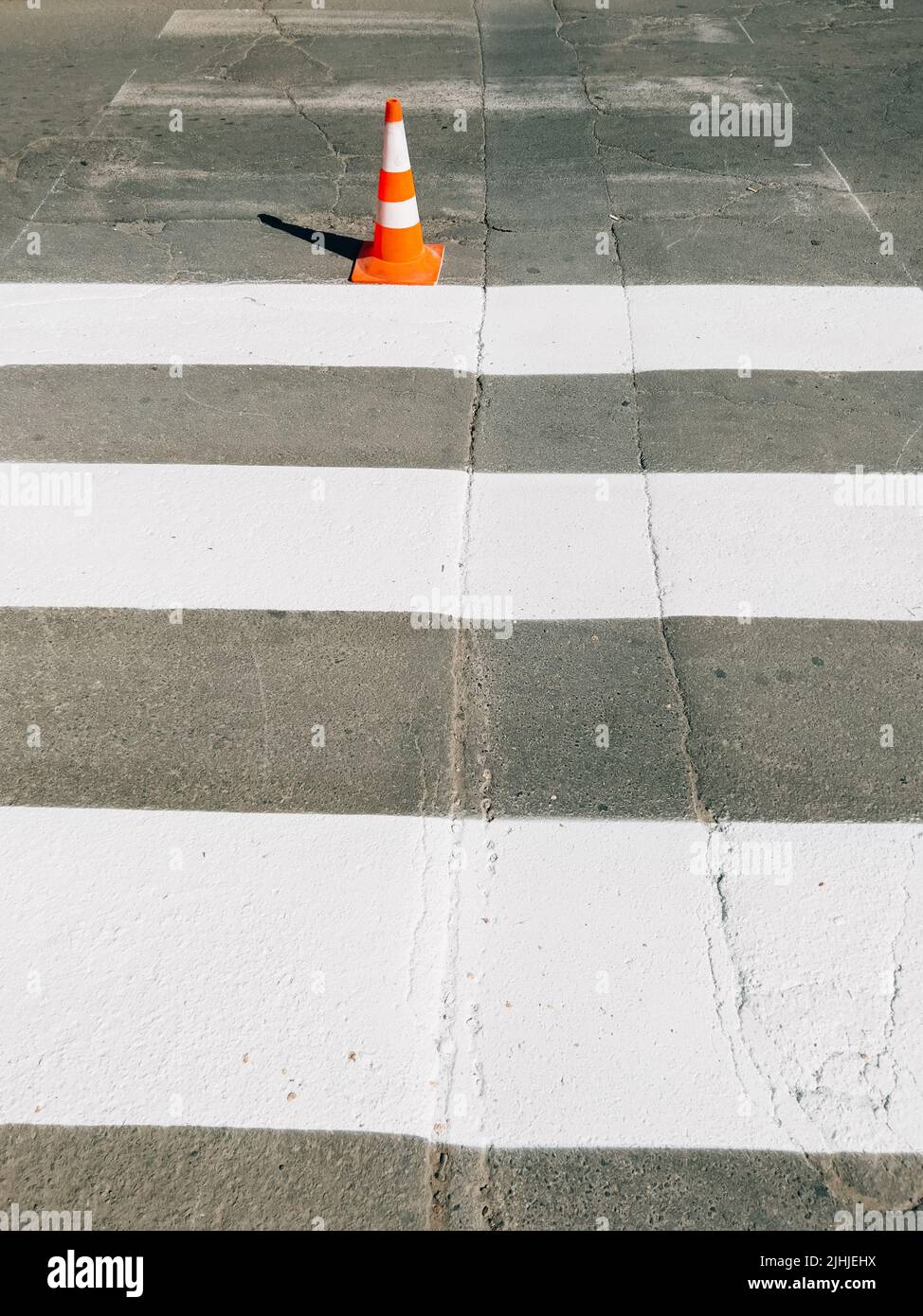 Zebra crossing marking paint on the road and orange traffic cone on the