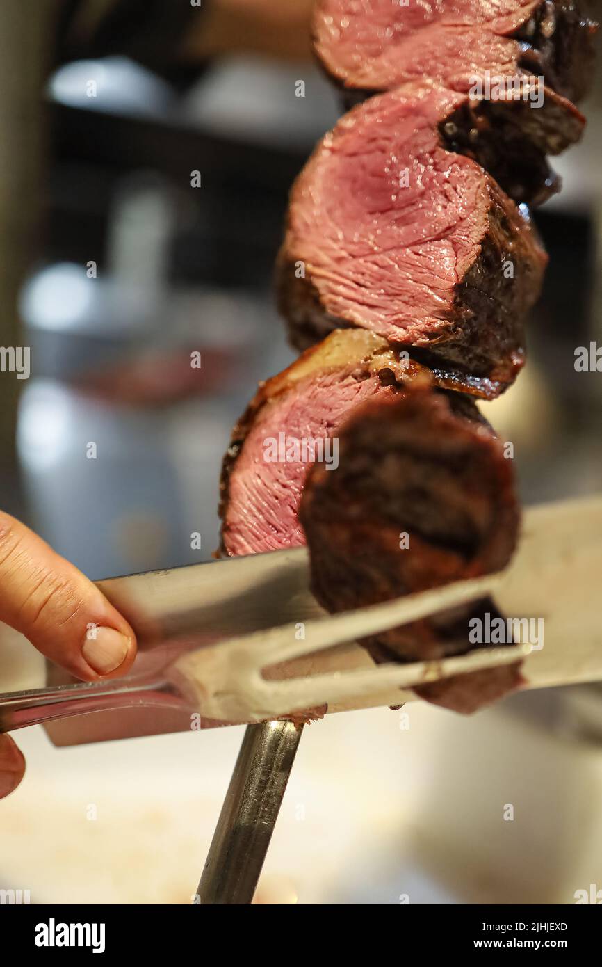 Churrasco meat on a cutting board next to a knife