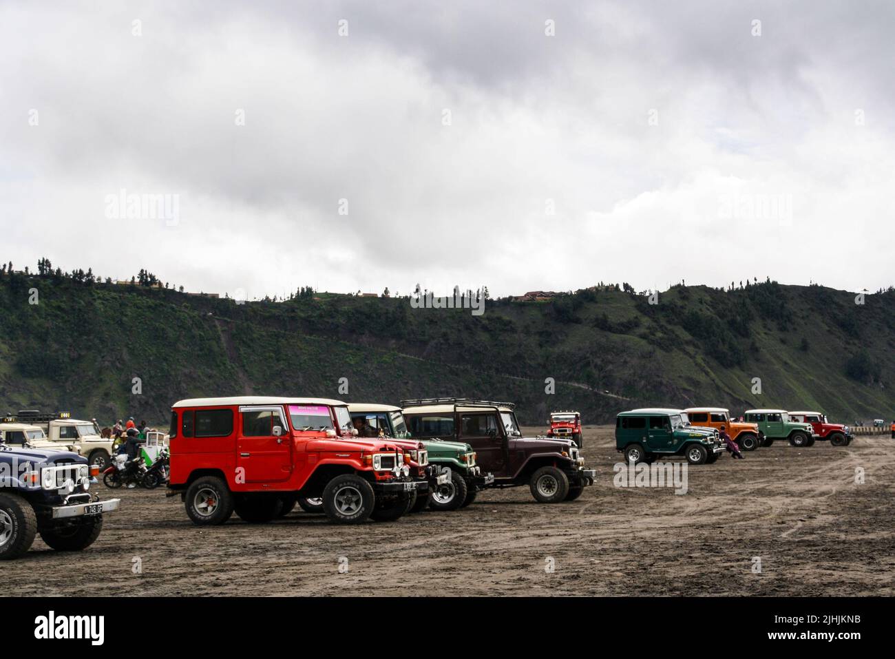 Vintage Japanese jeep parking in line for tourist transport at Mount Bromo in the Tengger Semeru National Park with cloudy sky background. Stock Photo