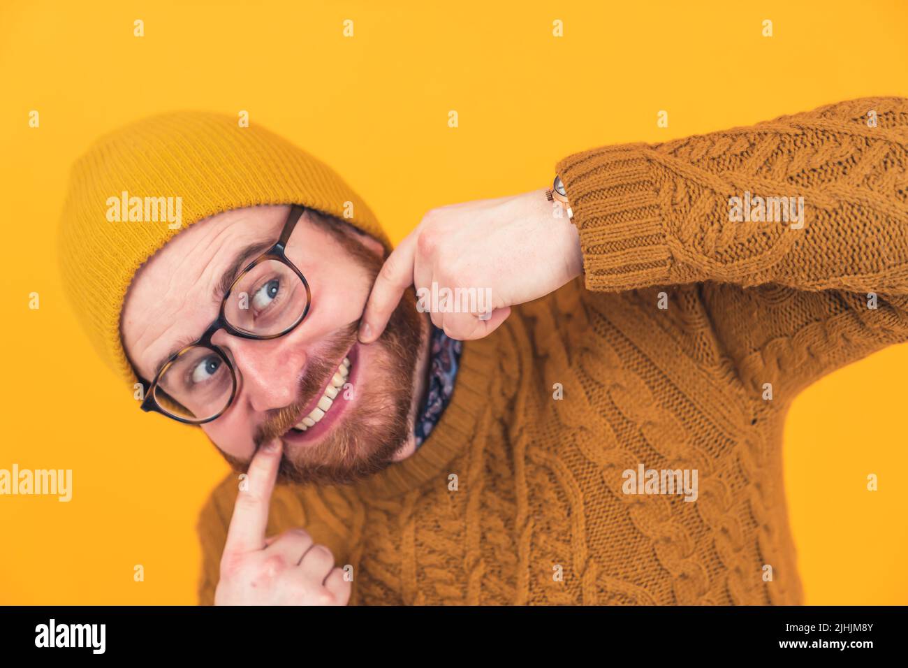 Funny bearded guy showing his teeth and fooling around - orange studio background. High quality photo Stock Photo